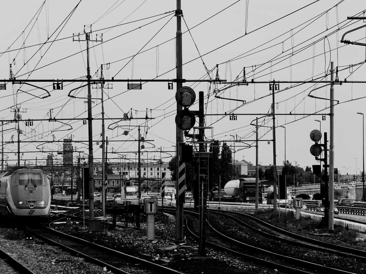 Rail yard dense with overhead wiring and a signal gantry
